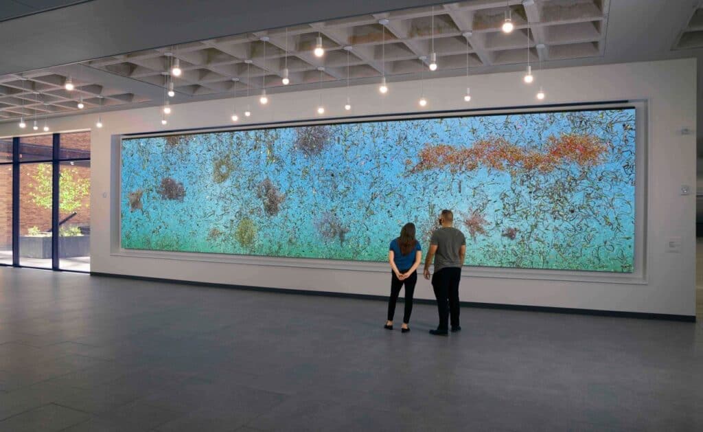 “EON” is an art installation created using digital animation and displayed on a large flat wall panel. The digital video features biomorphic shapes of various sizes and colors moving across the screen on a bright blue background.
