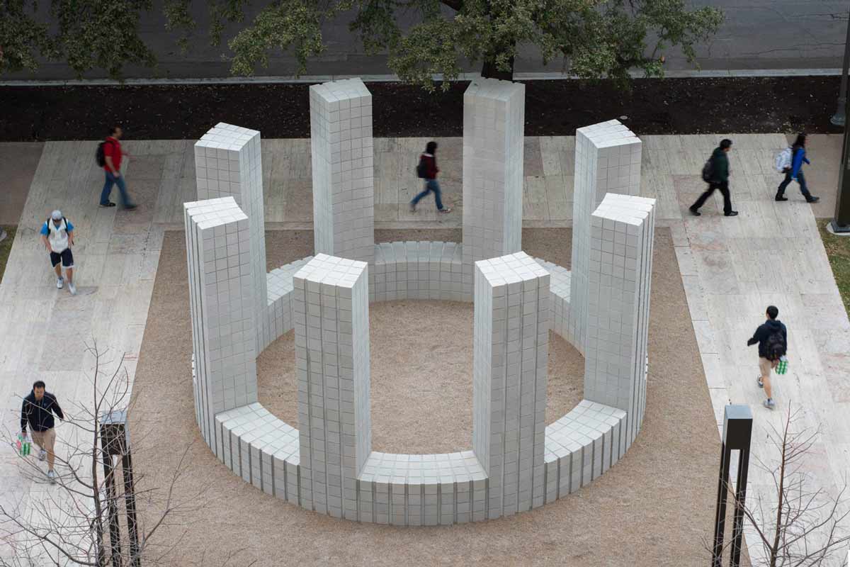 "Circle with Towers" is an art installation consisting of a low circular wall capped at regular intervals by eight rectangular towers made of pale gray concrete blocks located in a courtyard at The University of Texas at Austin