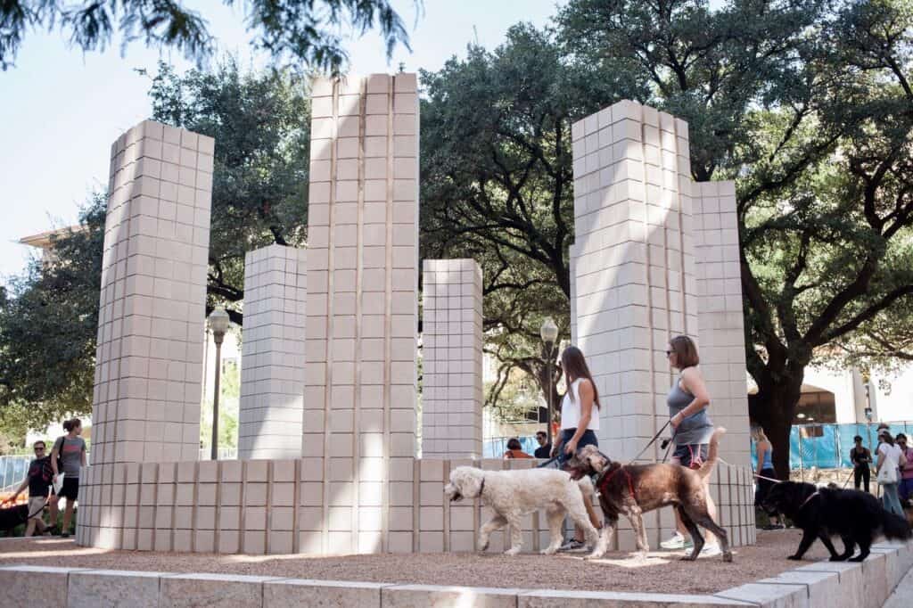 "Circle with Towers" is an art installation consisting of a low circular wall capped at regular intervals by eight rectangular towers made of pale gray concrete blocks located in a courtyard at The University of Texas at Austin
