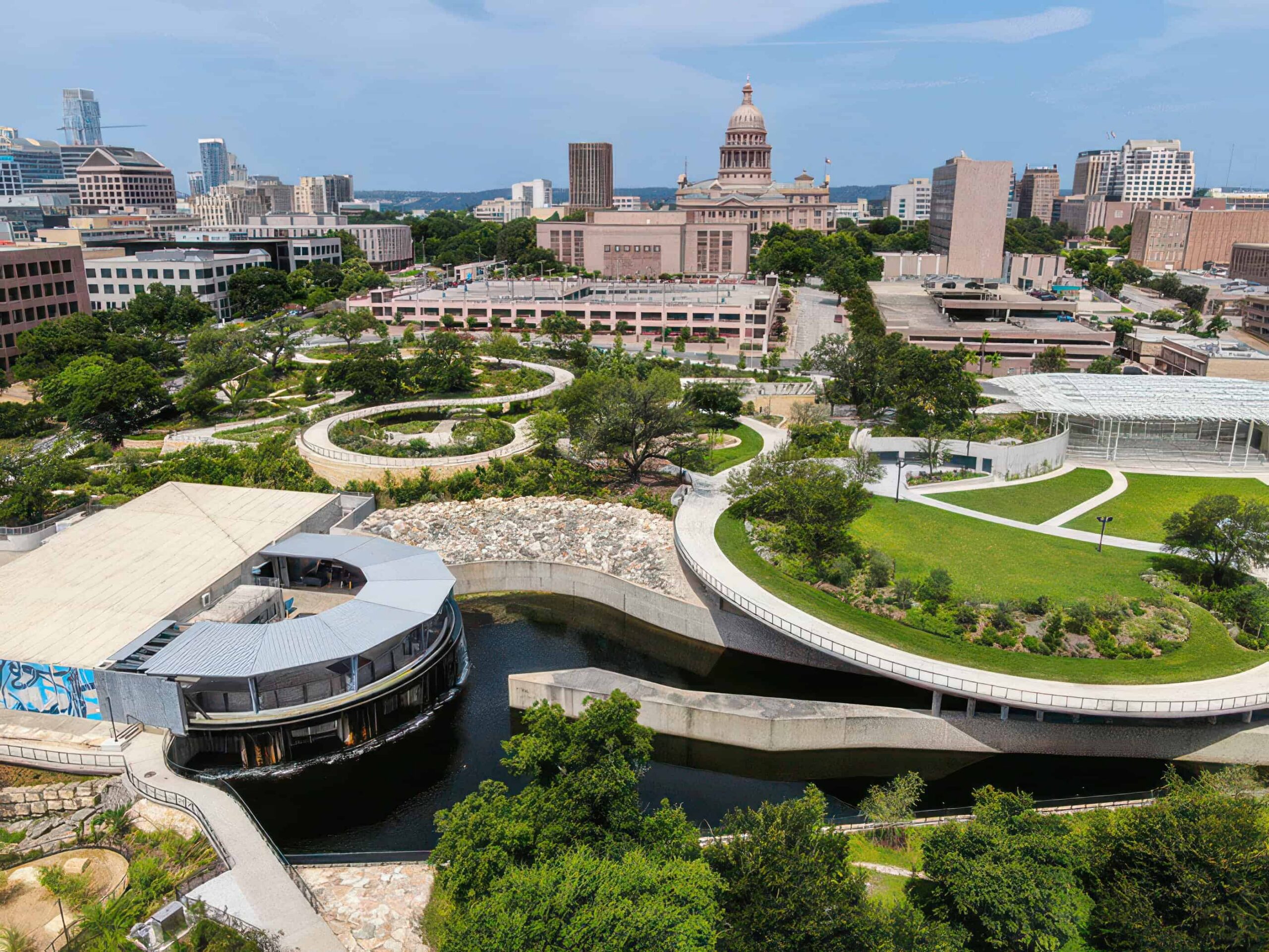 Aerial view of Waterloo Greenway in Austin, TX with green spaces and shaded paths.
